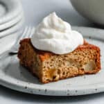 Fruit Cocktail Cake on a grey plate topped with whipped cream