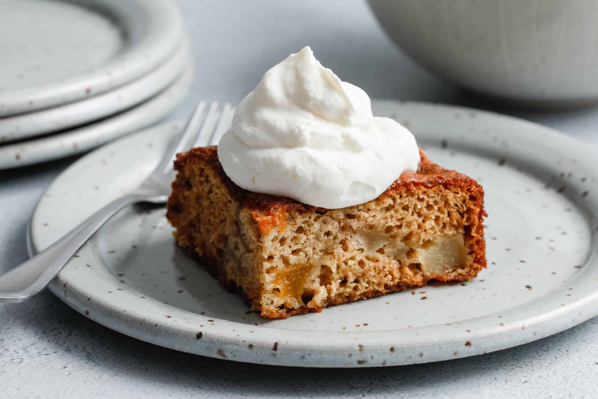 Fruit Cocktail Cake on a grey plate topped with whipped cream