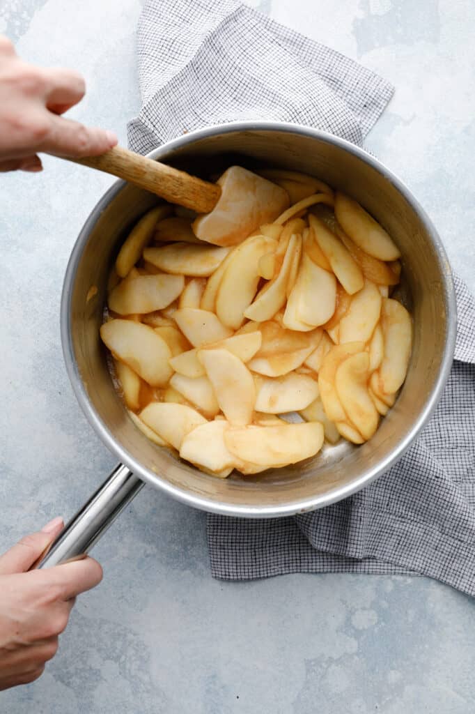 An overhead view of a pot of apples being cooked with spices and maple syrup in preparation for being put into a tart