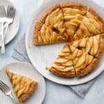 overhead image of an apple tart sliced with a slice on a separate plate