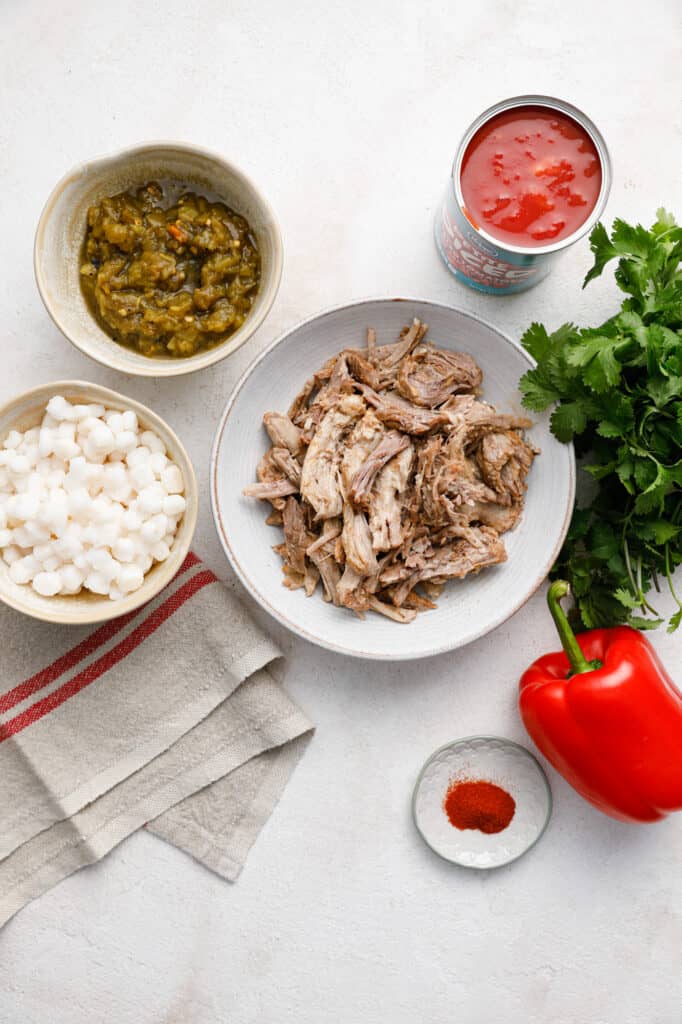view of ingredients for leftover pork posole including pulled pork, green chilies, tomatoes, onion, pepper and spices