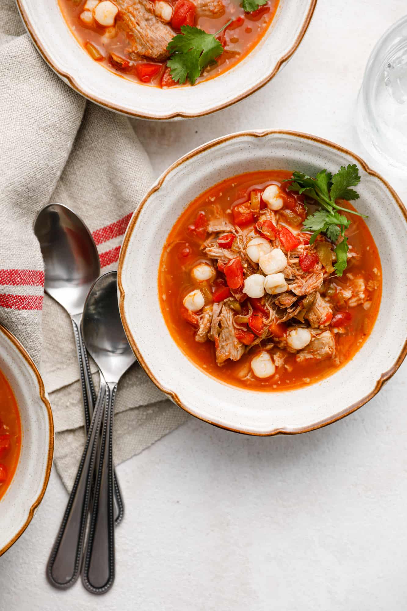 overhead image of bowls of red posole with pork and hominy