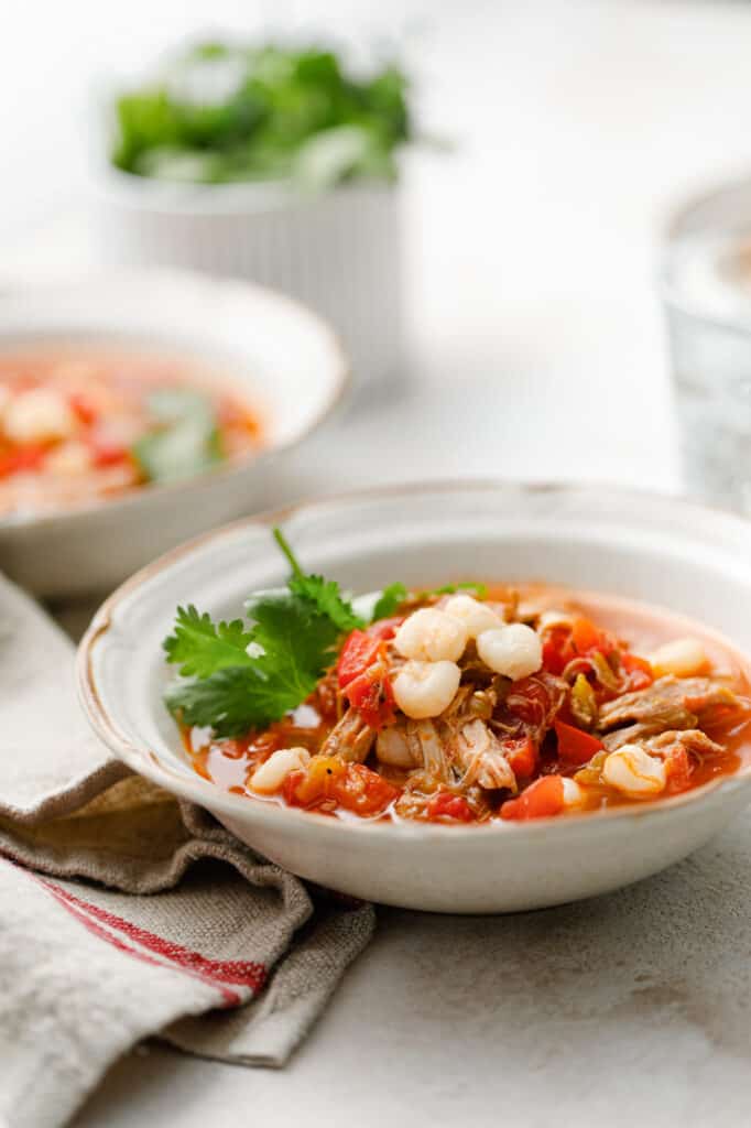 a bowl of leftover pork posole soup with fresh cilantro as a garnish