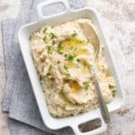 overhead view of a dish full of mashed cauliflower with pools of butter
