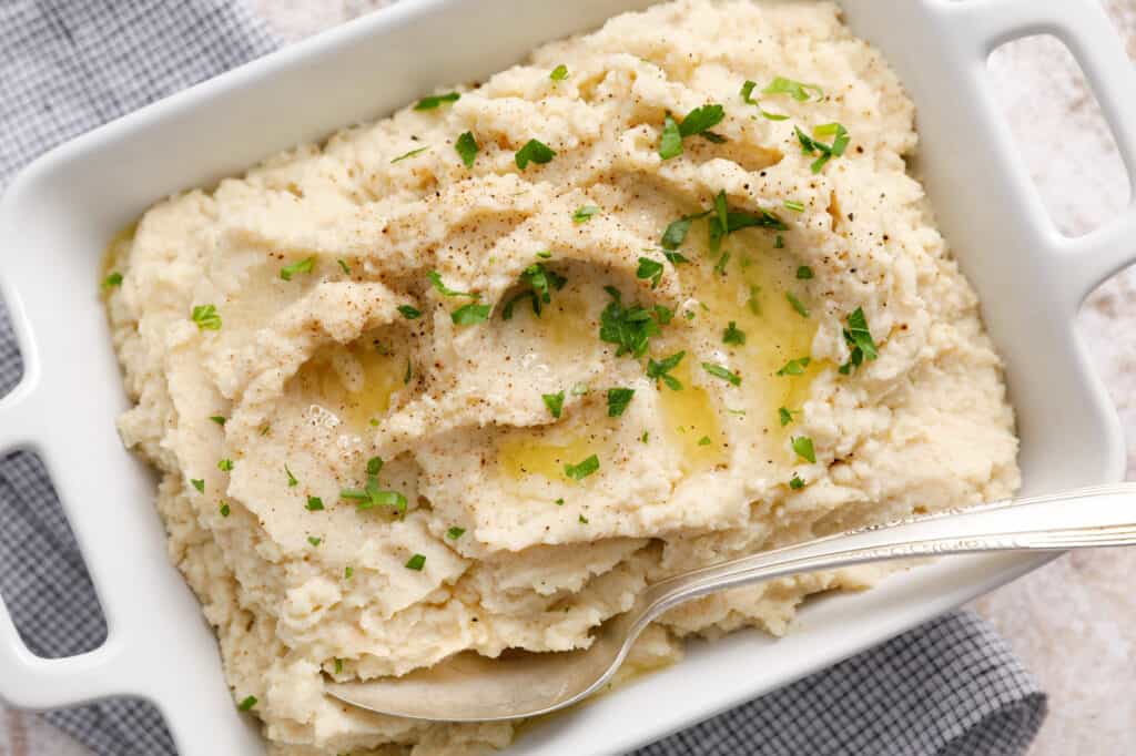overhead view of a dish full of mashed cauliflower with pools of butter
