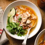 green chile pork stew in a bowl garnished with lime and cilantro