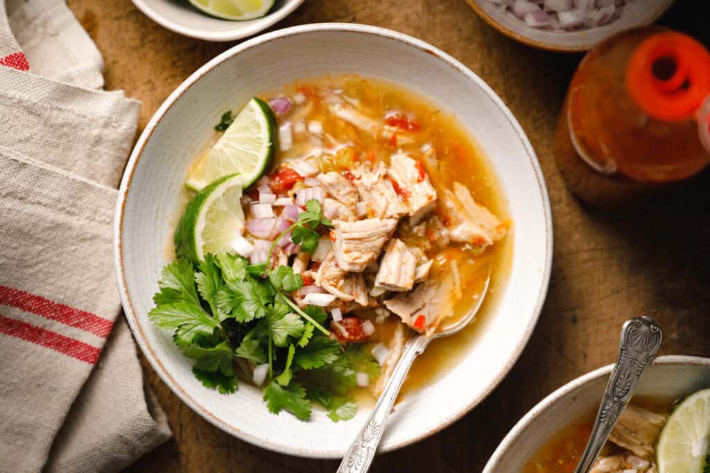 green chile pork stew in a bowl garnished with lime and cilantro
