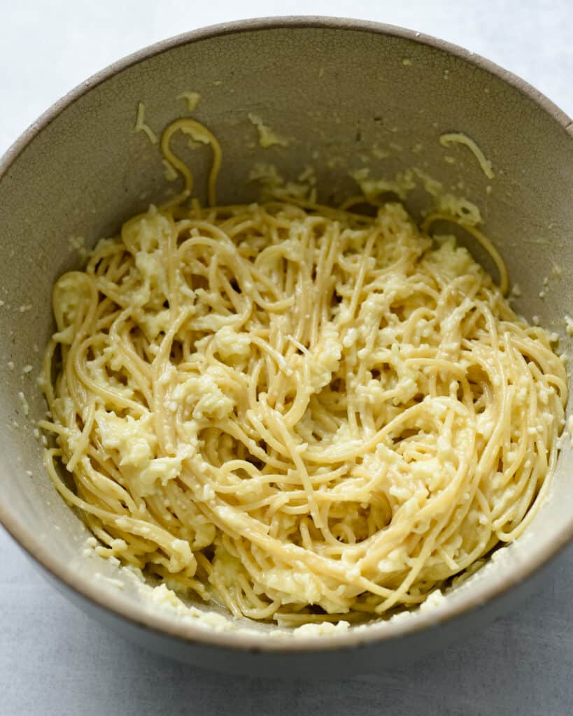 The spaghetti pasta in a bowl with egg and cheese before it becomes the crust