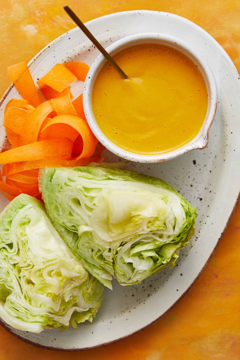 overhead view of dressing, lettuce and shredded carrots