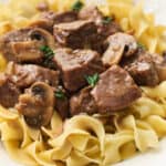 Closeup of beef tips plated on egg noodles