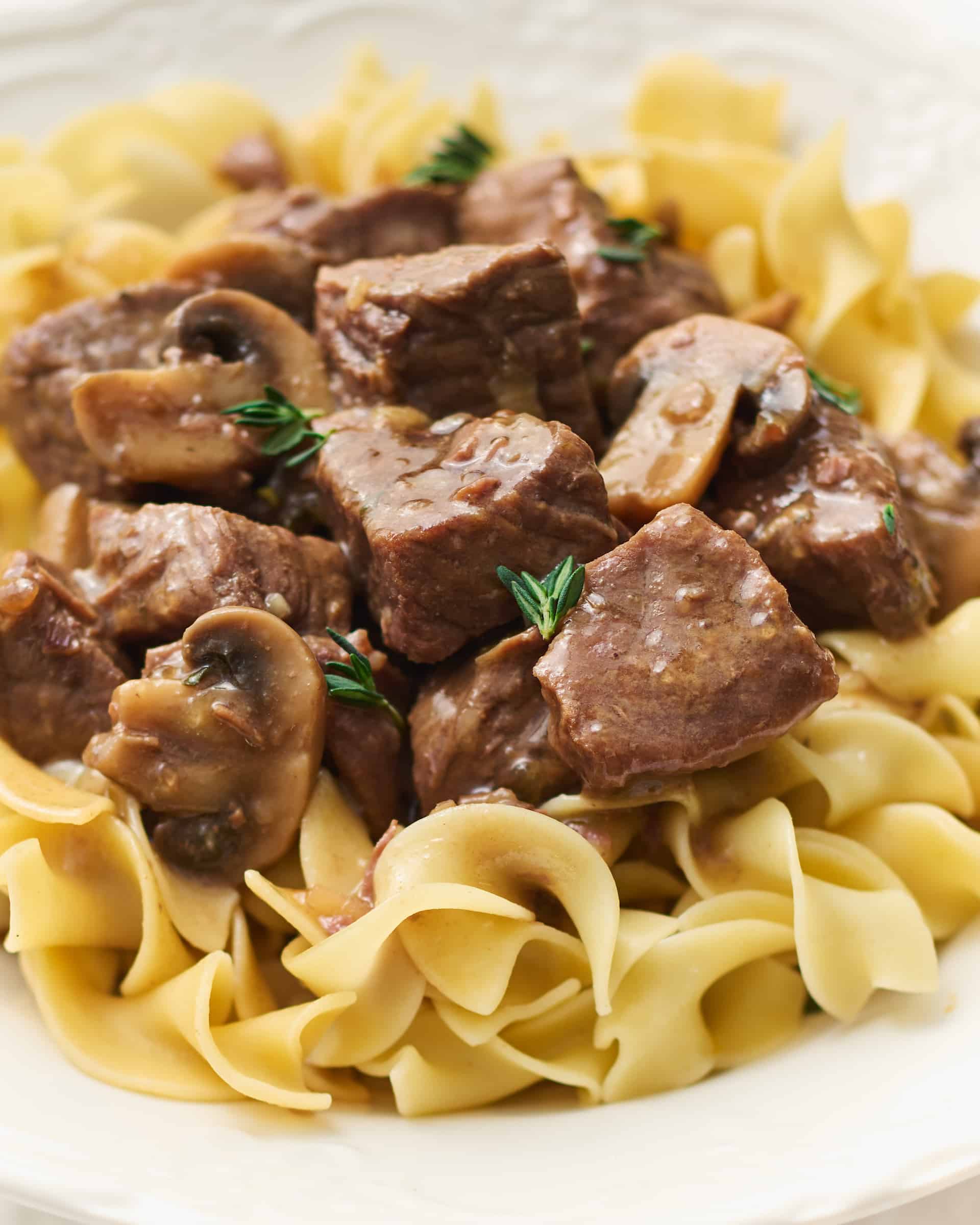 Closeup of beef tips plated on egg noodles