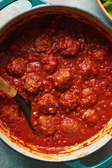 Homemade meatballs in zesty tomato marinara sauce in a large dutch oven.