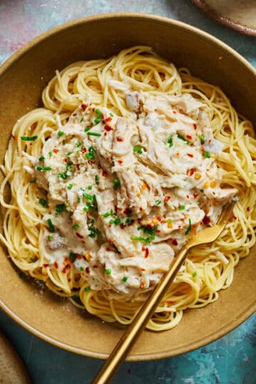 Crock Pot Angel Chicken on a bed of pasta in a bowl with red pepper flakes