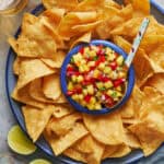 overhead view of a platter of tortilla chips with pineapple pico de gallo in the center with a spoon