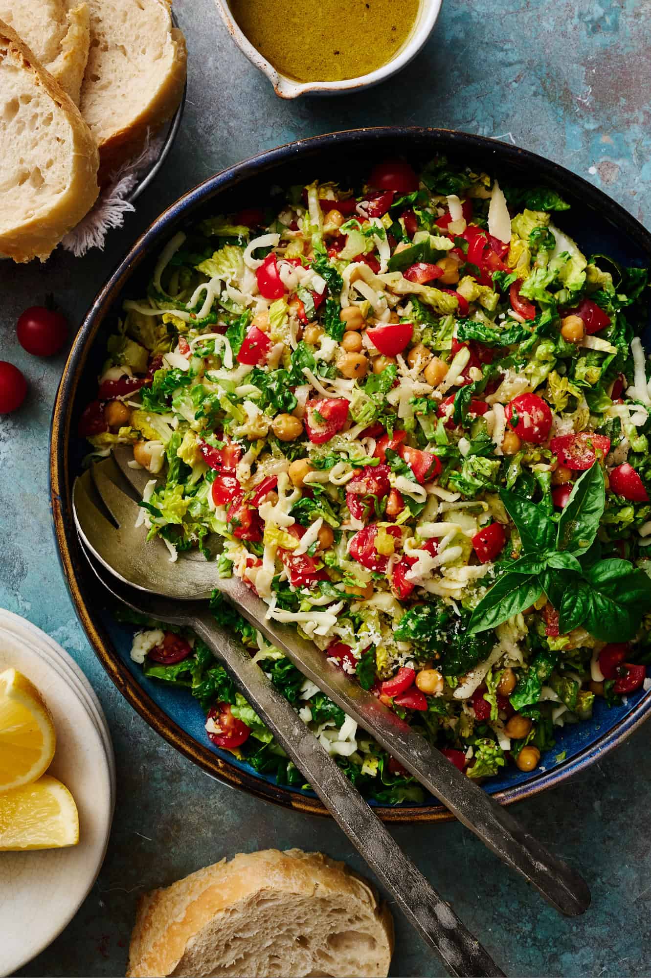 bowl full of caprese chopped salad with tongs for serving with sourdough bread on the side