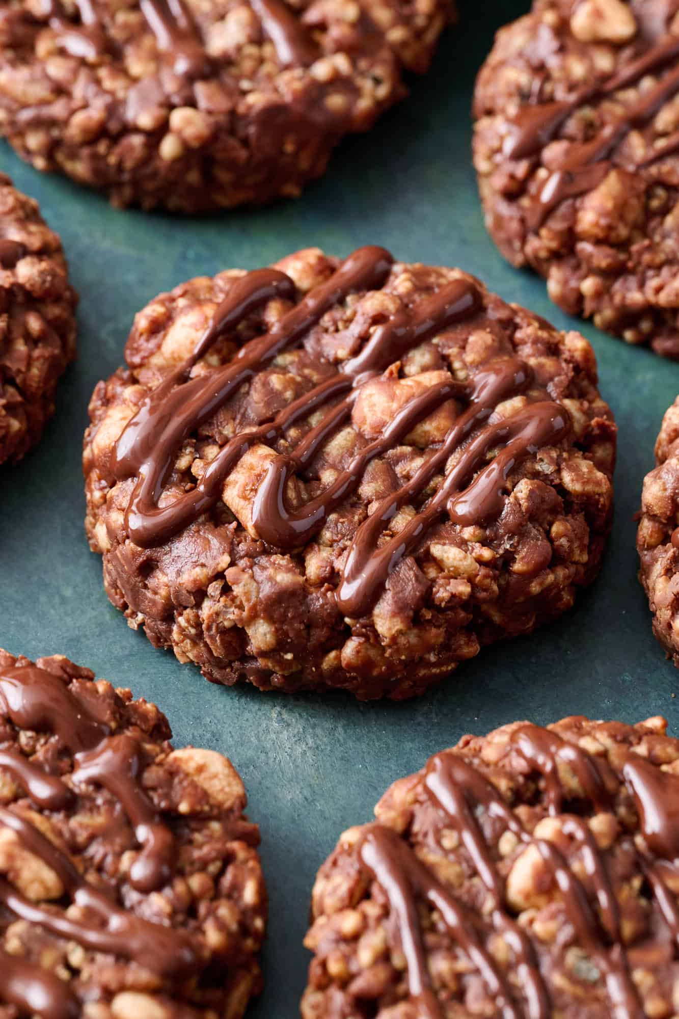chocolate rice krispie cookies on a green background drizzled with chocolate