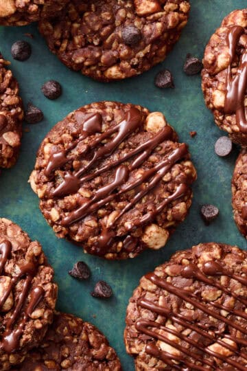 finished chocolate no bake rice Krispie cookies on a green background drizzled with chocolate