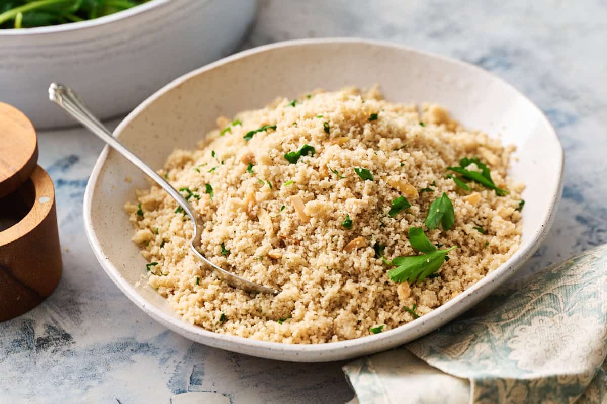 Fonio pilaf in a serving bowl garnished with herbs