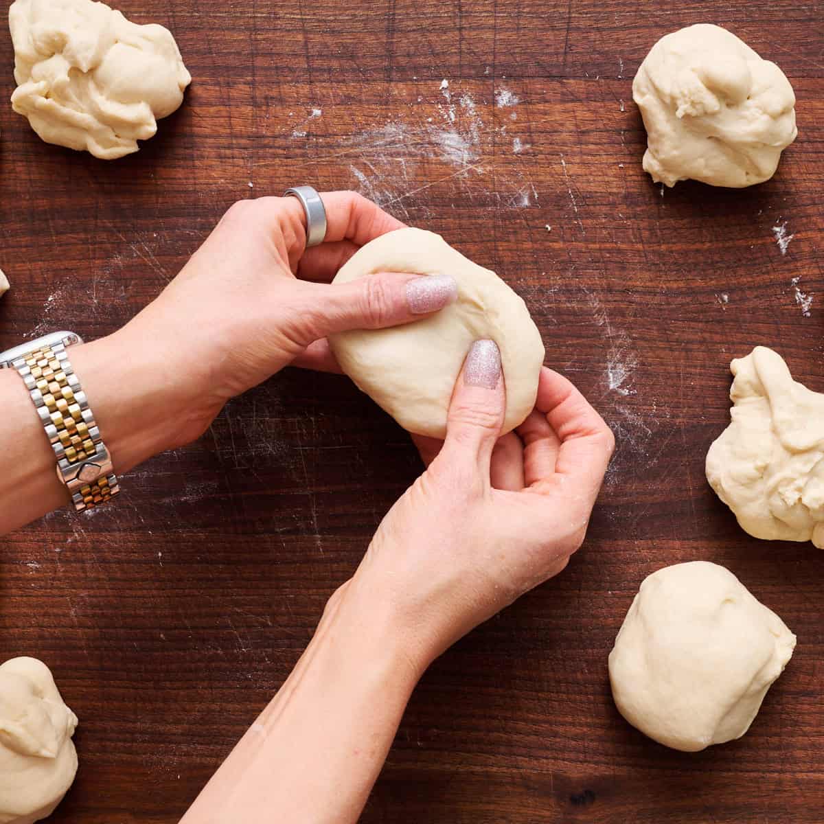 two hands shaping the english muffin dough
