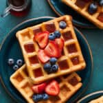 sour cream waffles on plates topped with berries and maple syrup