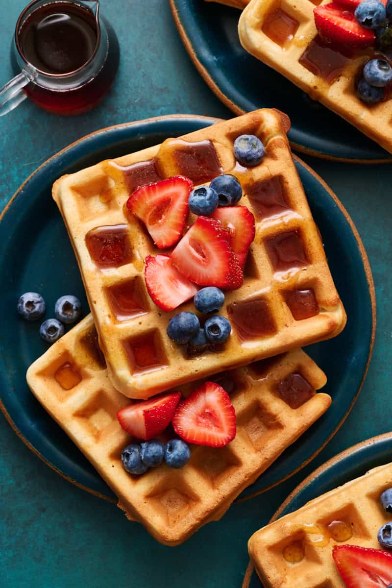 sour cream waffles on plates topped with berries and maple syrup