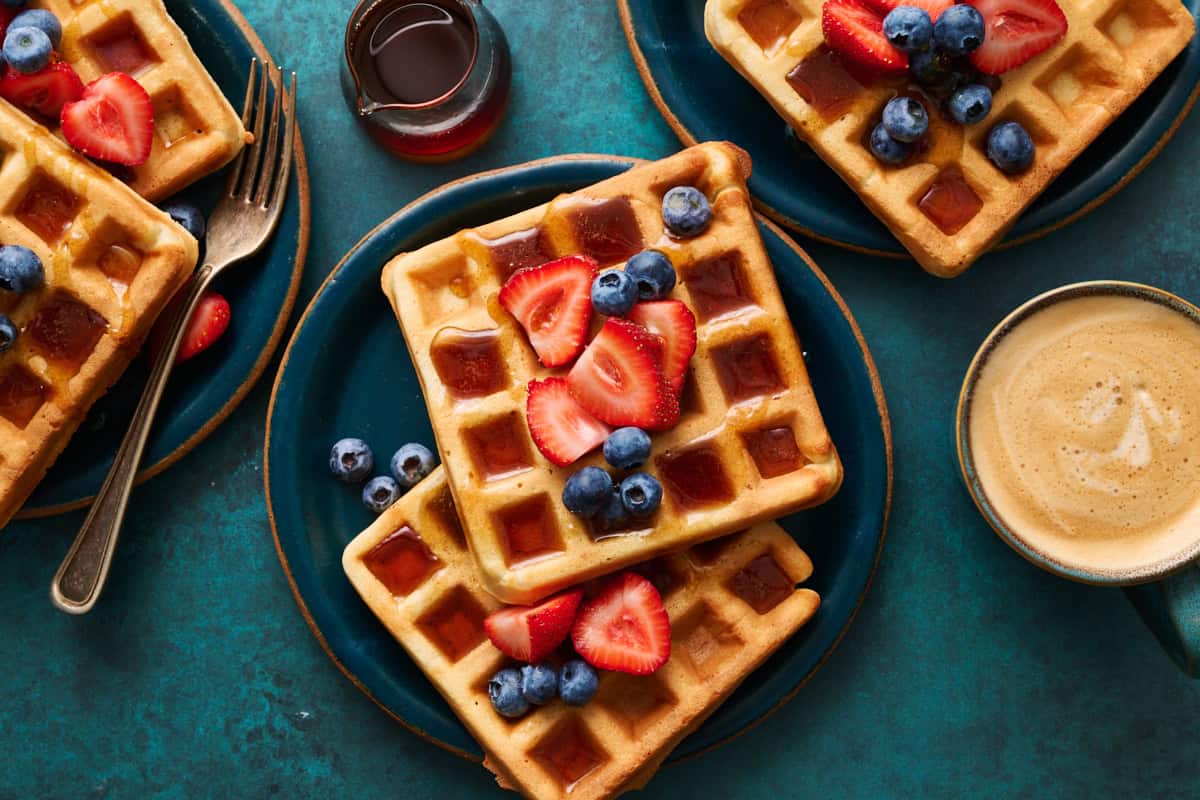 sour cream waffles on plates topped with berries and maple syrup