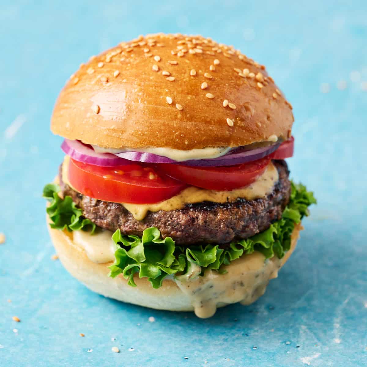 a hamburger loaded with meat, lettuce, tomatoes, onion and special sauce
