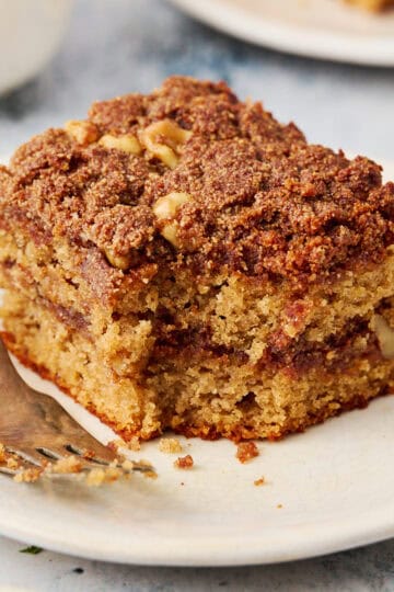 a slice of coffee cake on a plate with a fork with a bite taken out