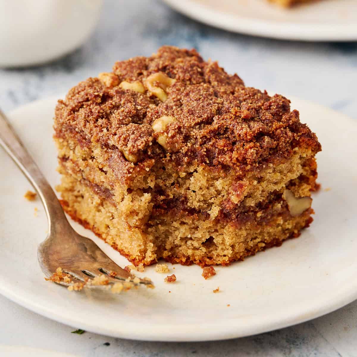 a slice of coffee cake on a plate with a fork with a bite taken out