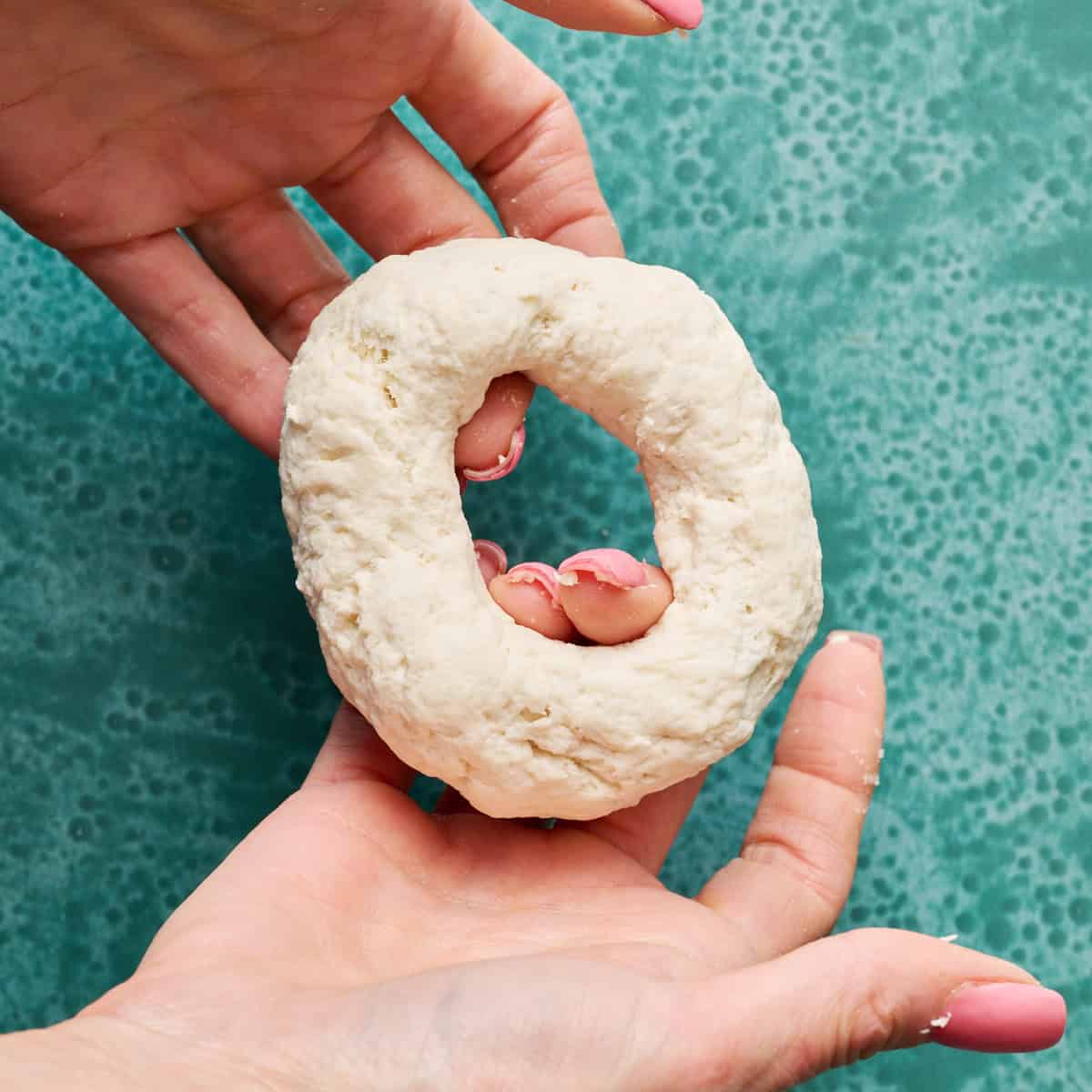 stretching out the ring to make a hole in the center of the dough for a bagel