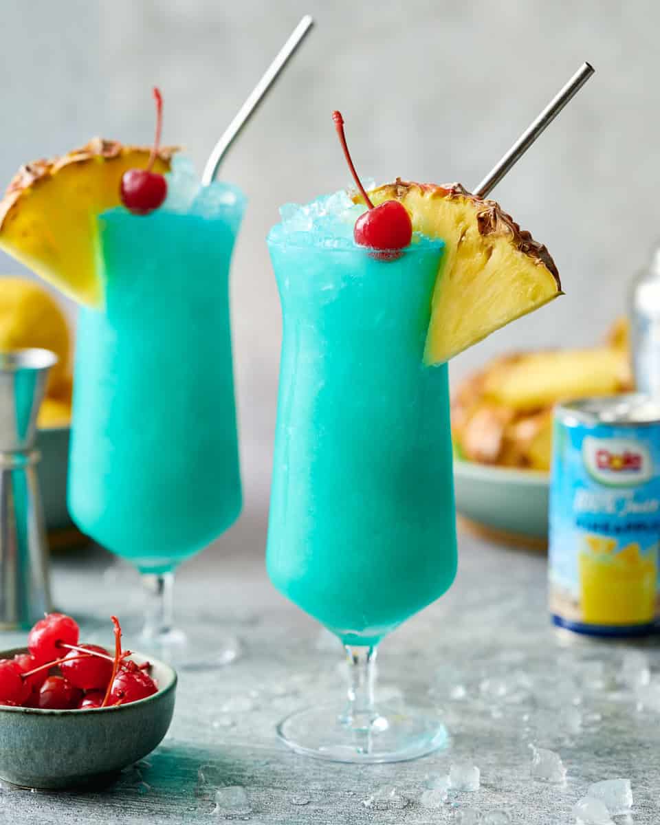 finished blue hawaii mocktails garnished with fresh pineapple and cherries