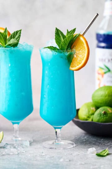 blue ocean mocktails in hurricane glasses with mint and orange