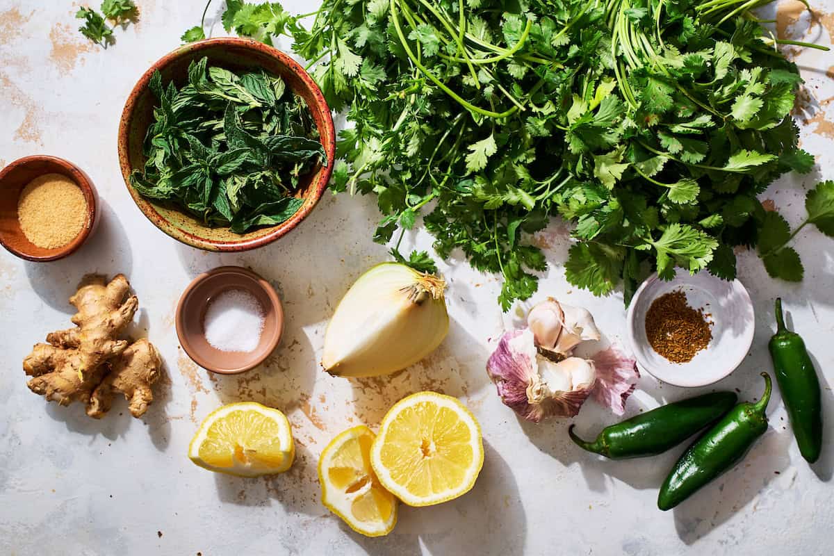 ingredients to make cilantro mint chutney including cumin, jalapeno, garlic, lemon, salt, ginger and sugar