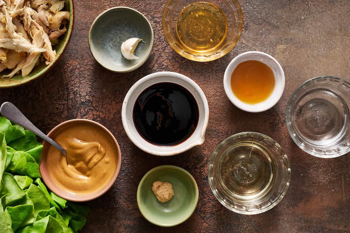 ingredients for making the peanut sauce laid out including garlic, soy sauce, peanut butter, sesame oil, ginger paste, rice wine vinegar, honey and water