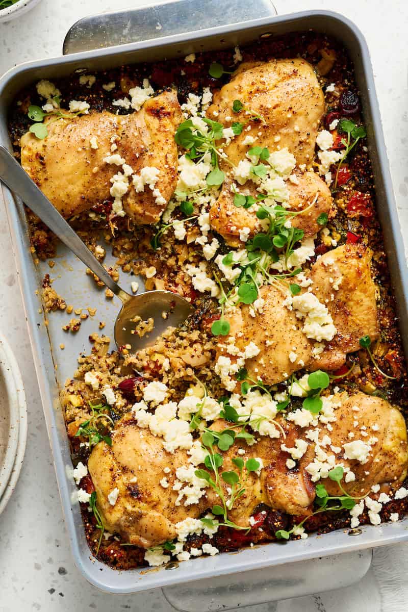 One pan Mediterranean chicken quinoa bake plated in a dish with golden brown chicken thighs, crumbled feta cheese