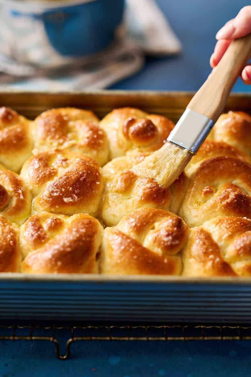 brushing garlic knot rolls with garlic butter
