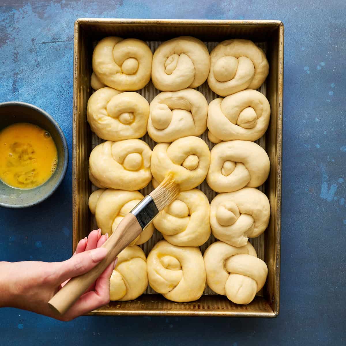 risen dough being brushed with egg wash
