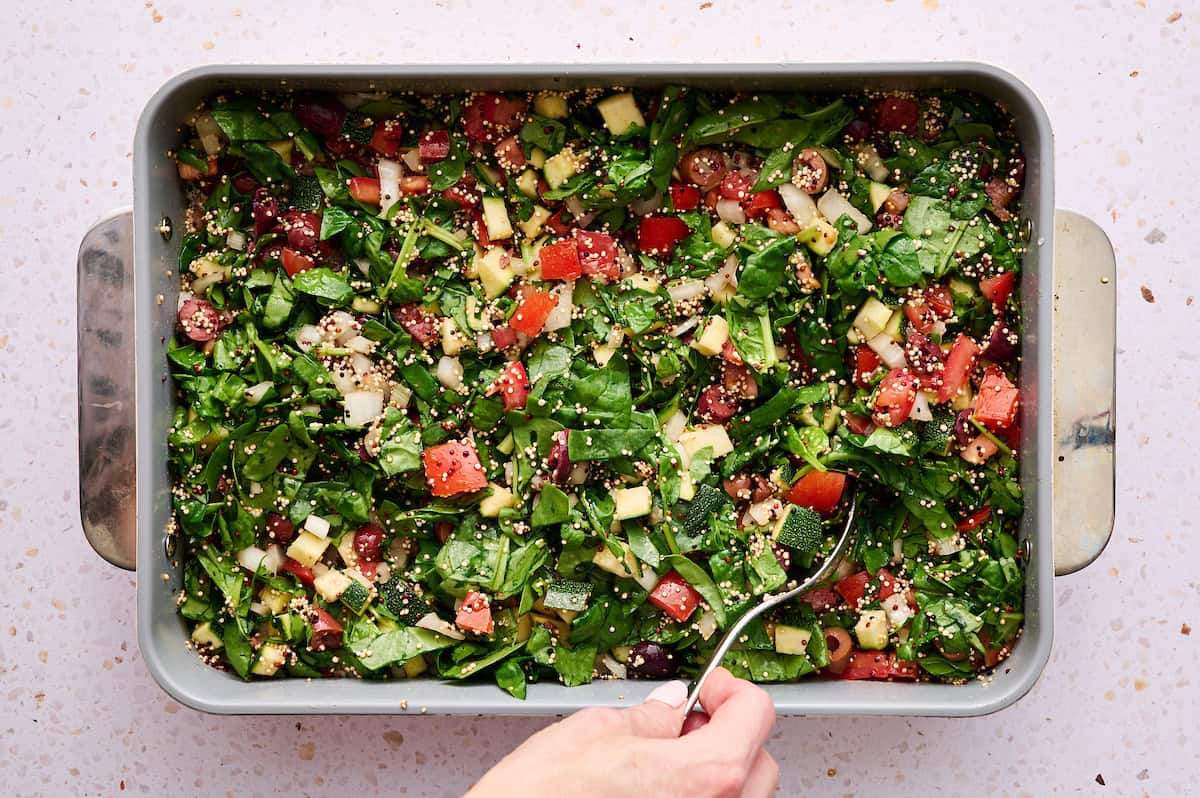 Mixing together the veggies and quinoa in a baking dish