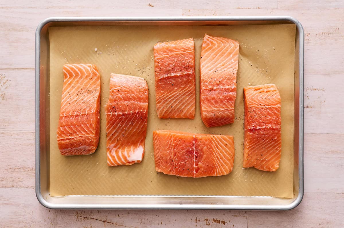 fresh salmon filets seasoned and ready to cook on a baking tray