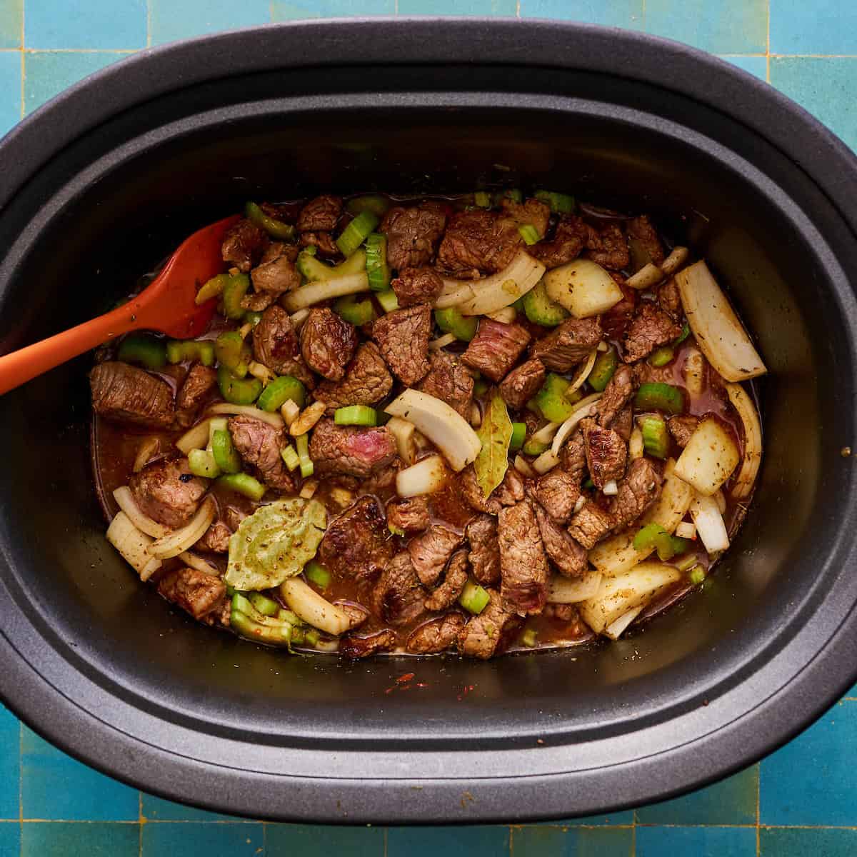 meat, celery, bay leaves, onions garlic and broth added to the slow cooker