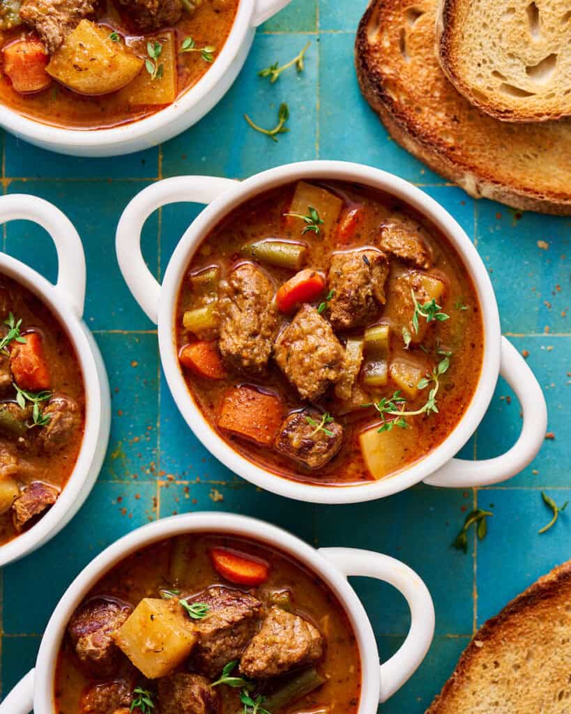 slow cooker beef stew in a white bowl with bread on the side