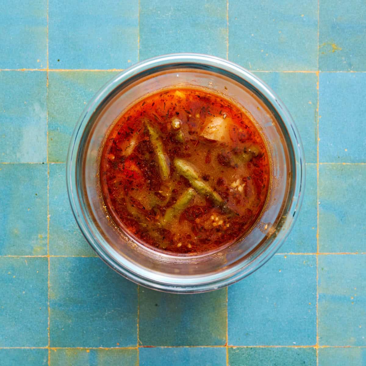 a cup of broth with veggies in a glass jar ready to be blended