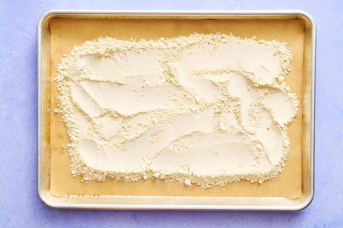 quinoa flour spread on a baking sheet with parchment
