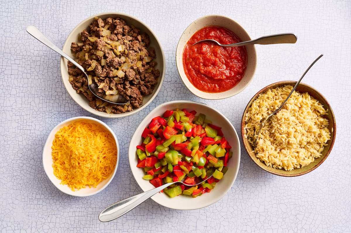 components of build your own pepper bowls with rice, seasoned beef, marinara, cheese and sauteed peppers
