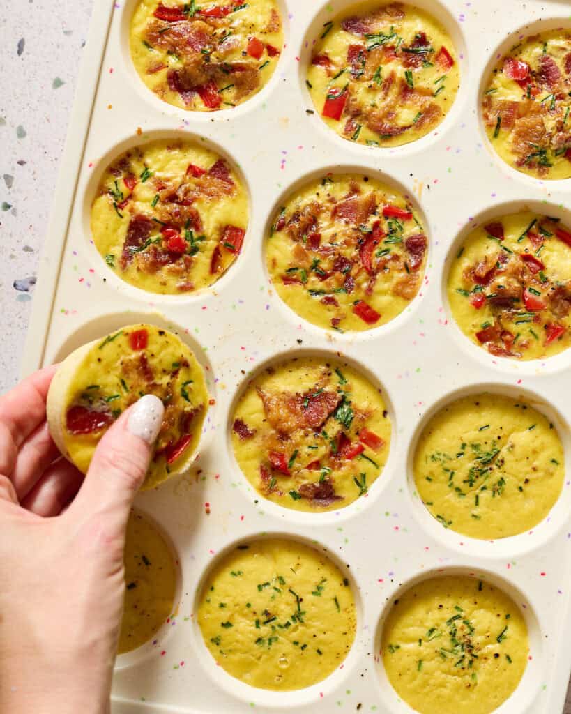 egg bites in a muffin tin and a hand pulling one out