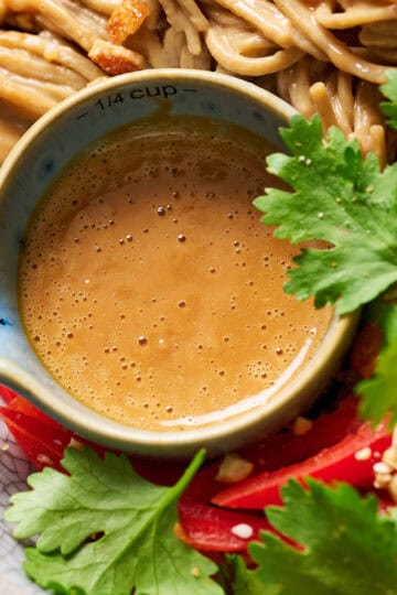 homemade peanut sauce in a small bowl with noodles and veggies for dressing