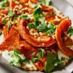 plated roasted squash with whipped ricotta and cilantro and pine nuts on the side