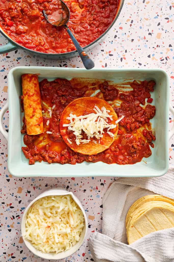 filing the enchiladas with beef, sauce and cheese