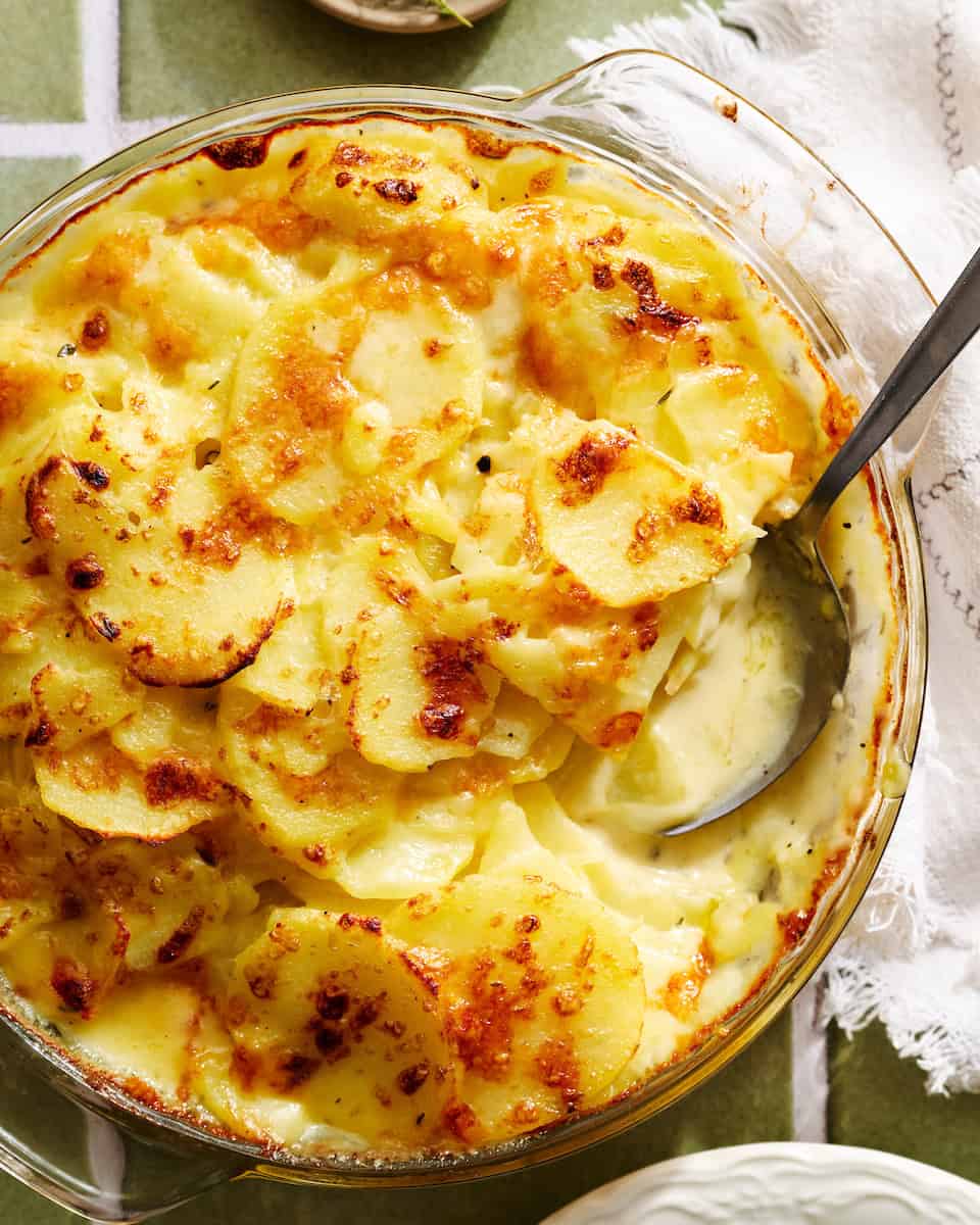 a dish of scalloped potatoes with a serving spoon in it