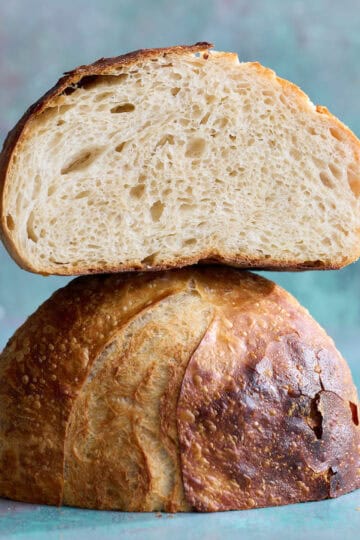 a loaf of sourdough bread sliced in half showing top and open crumb